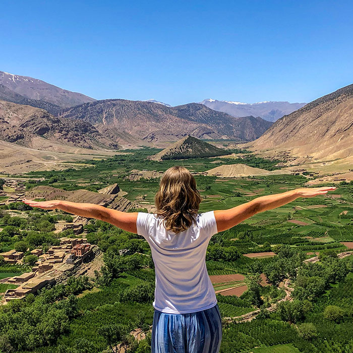 Woman standing with her arms out overlooking a valley in the Atlas Mountains